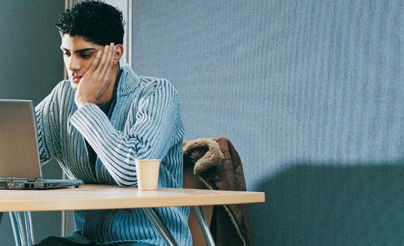 Male University Student Sitting at a Desk Using a Laptop Computer